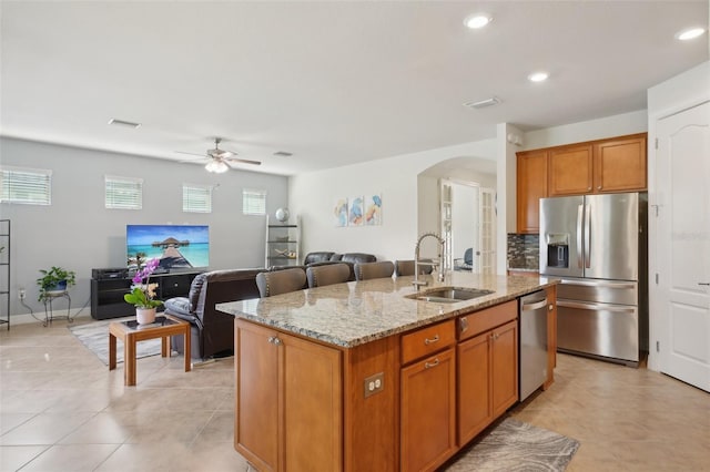 7580 Pool Compass Loop, Wesley Chapel, FL 33545 - kitchen featuring light stone counters, a sink, arched walkways, stainless steel appliances, and a ceiling fan