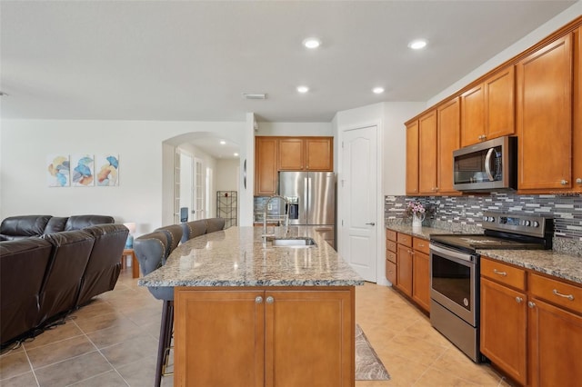 7580 Pool Compass Loop, Wesley Chapel, FL 33545 - kitchen with decorative backsplash, a sink, light tile patterned flooring, arched walkways, and appliances with stainless steel finishes