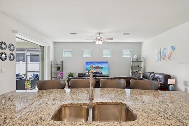 7580 Pool Compass Loop, Wesley Chapel, FL 33545 - kitchen featuring ceiling fan, light stone countertops, a sink, open floor plan, and visible vents