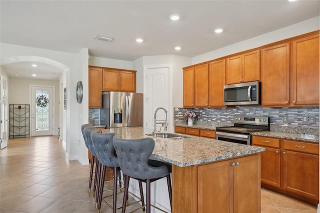 7580 Pool Compass Loop, Wesley Chapel, FL 33545 - kitchen featuring arched walkways, appliances with stainless steel finishes, backsplash, and light stone countertops