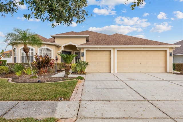 view of front facade featuring a garage, concrete driveway, and stucco siding