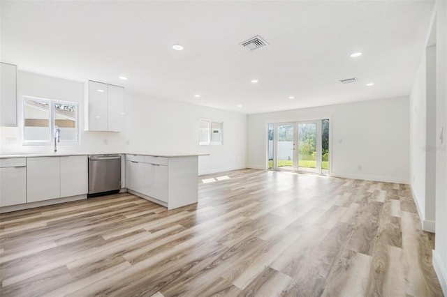 kitchen with white cabinetry, light hardwood / wood-style flooring, stainless steel dishwasher, kitchen peninsula, and french doors