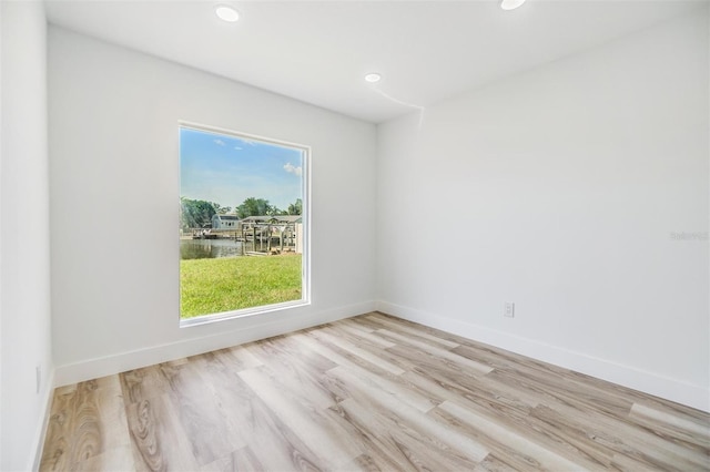 spare room with a water view and light wood-type flooring