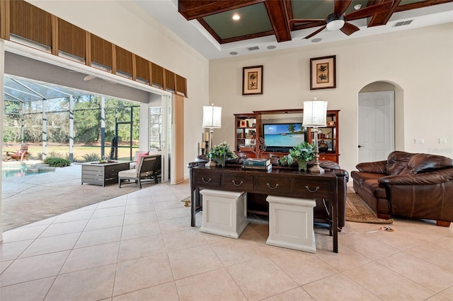 tiled home office with ceiling fan, coffered ceiling, beam ceiling, and a high ceiling