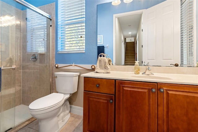 bathroom with tile patterned flooring, vanity, a shower with shower door, and toilet