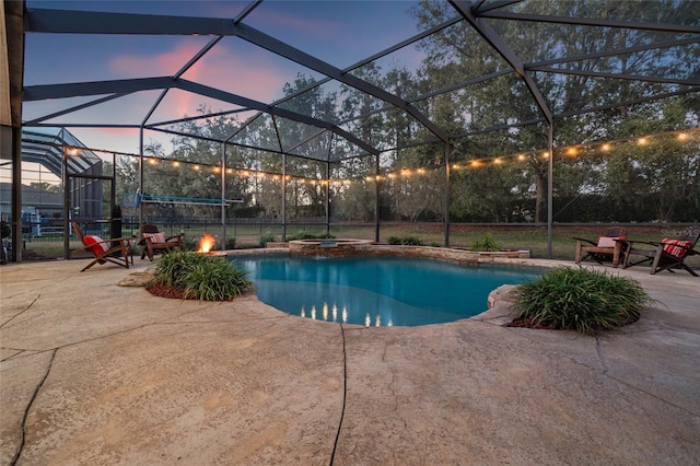 pool at dusk with a jacuzzi, a patio area, and glass enclosure