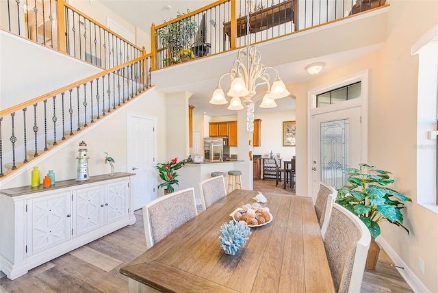 dining space featuring an inviting chandelier, a towering ceiling, and light hardwood / wood-style floors