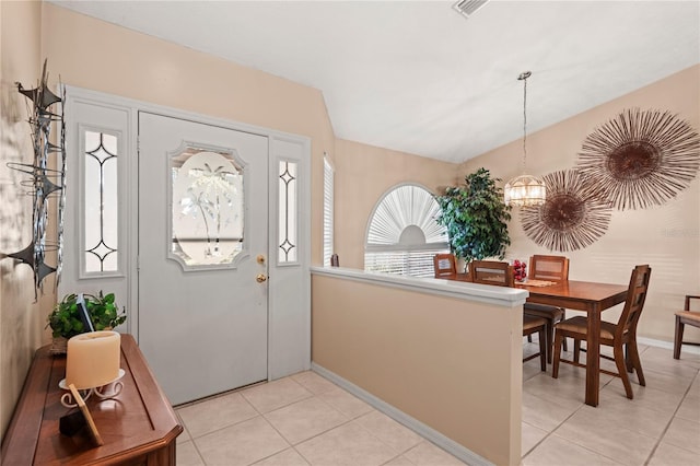 tiled foyer entrance with lofted ceiling and a notable chandelier