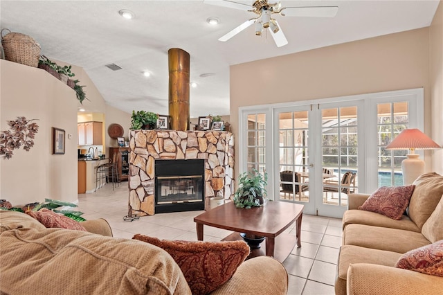 living room featuring lofted ceiling, a stone fireplace, french doors, and light tile patterned flooring