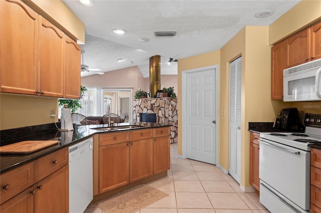 kitchen with sink, white appliances, a textured ceiling, light tile patterned flooring, and kitchen peninsula