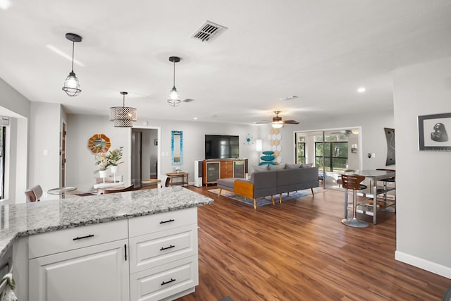 kitchen with white cabinetry, dark hardwood / wood-style flooring, pendant lighting, ceiling fan, and light stone countertops