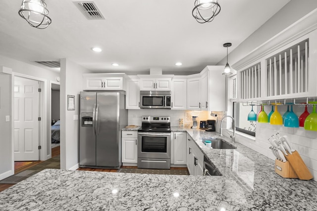 kitchen with pendant lighting, white cabinetry, sink, stainless steel appliances, and light stone countertops