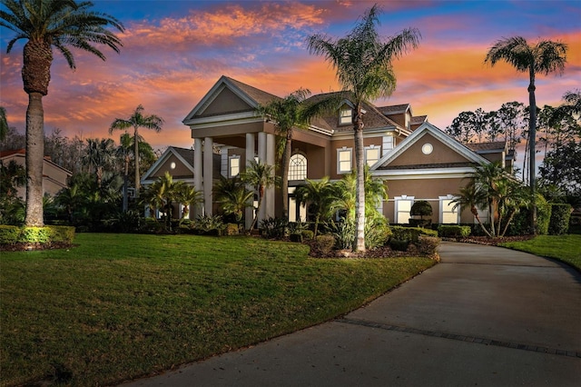 view of front facade featuring driveway, a front lawn, and stucco siding