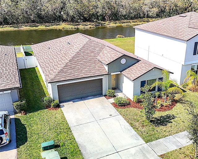 view of front of house with a garage, a front yard, concrete driveway, and a water view