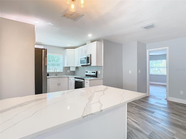 kitchen featuring sink, white cabinetry, light stone counters, appliances with stainless steel finishes, and decorative backsplash