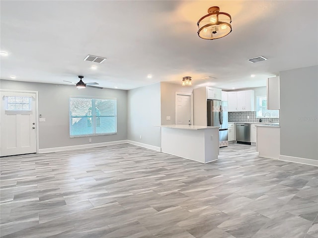 unfurnished living room featuring sink and ceiling fan