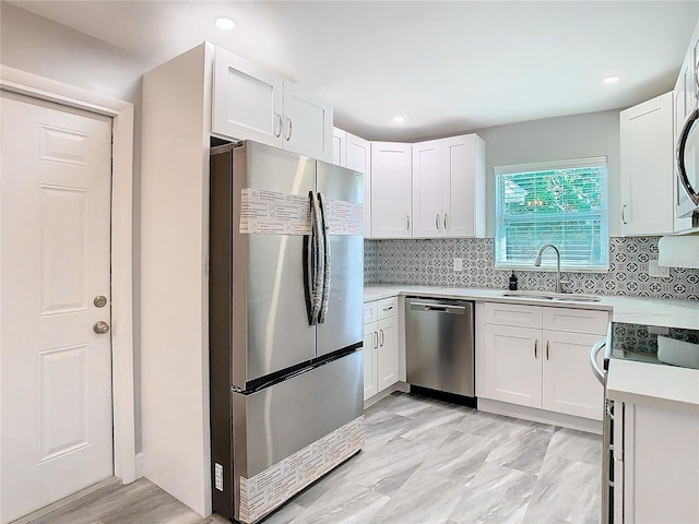 kitchen with stainless steel appliances, sink, white cabinets, and backsplash