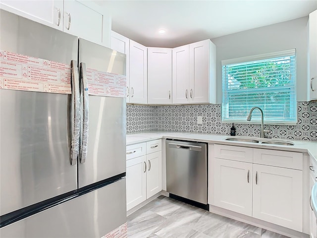 kitchen featuring tasteful backsplash, white cabinetry, appliances with stainless steel finishes, and sink