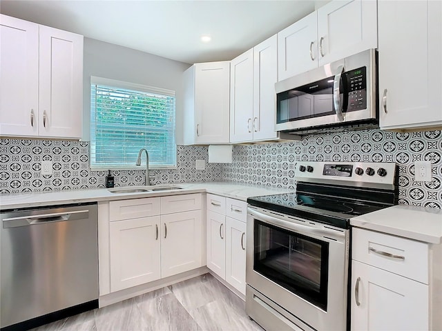 kitchen featuring stainless steel appliances, white cabinetry, sink, and decorative backsplash