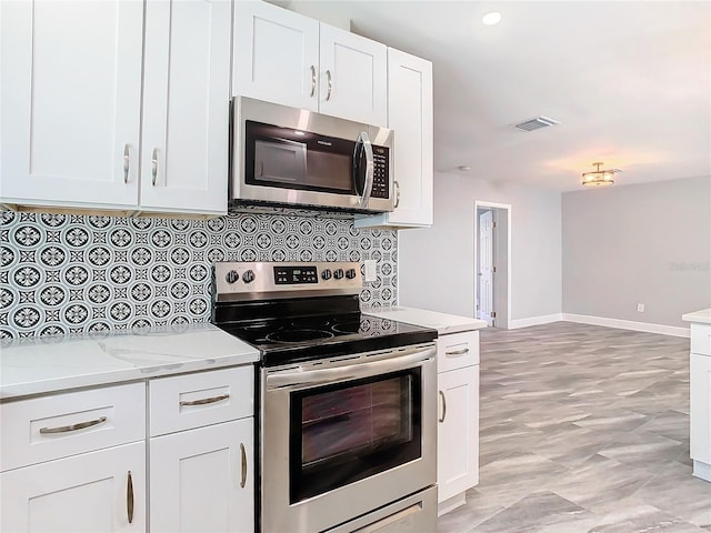 kitchen featuring white cabinetry, tasteful backsplash, light stone countertops, and appliances with stainless steel finishes