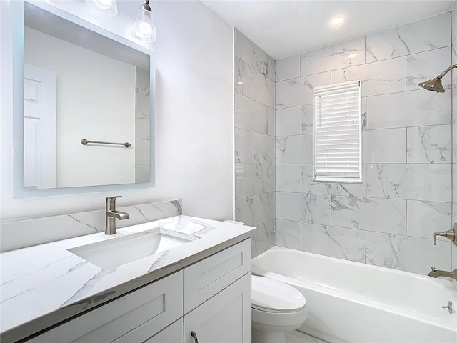 full bathroom featuring tiled shower / bath combo, vanity, and toilet