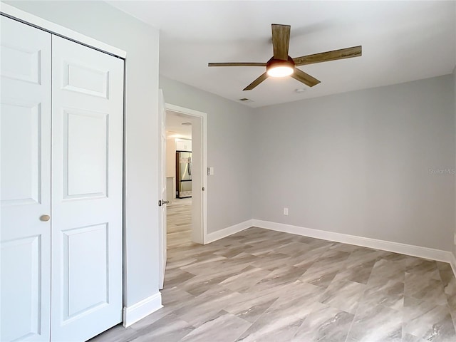 unfurnished bedroom with stainless steel refrigerator, ceiling fan, and a closet