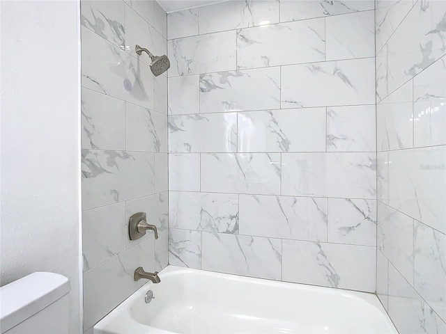 bathroom featuring tiled shower / bath and toilet