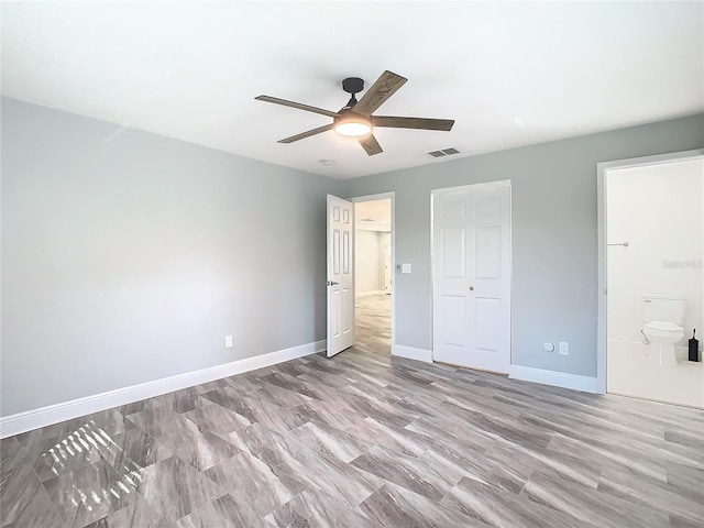 unfurnished bedroom with ceiling fan, ensuite bath, and a closet