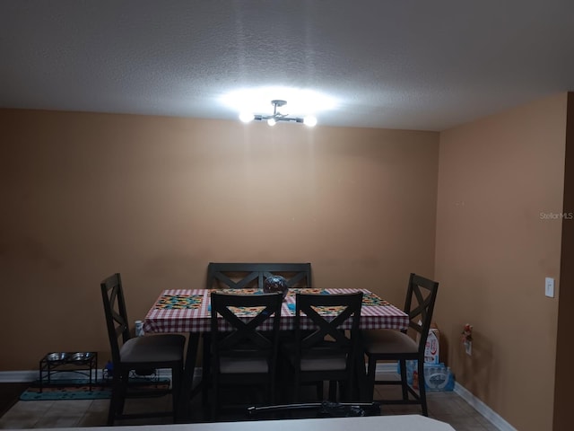 tiled dining area featuring an inviting chandelier and a textured ceiling