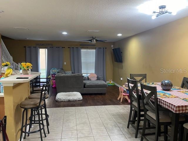 tiled dining space with ceiling fan and a textured ceiling