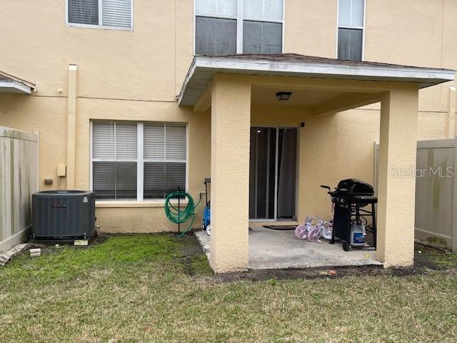 rear view of property with central AC unit, a yard, and a patio