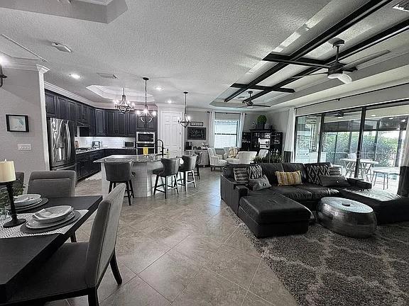 living room featuring crown molding, ceiling fan with notable chandelier, and a textured ceiling