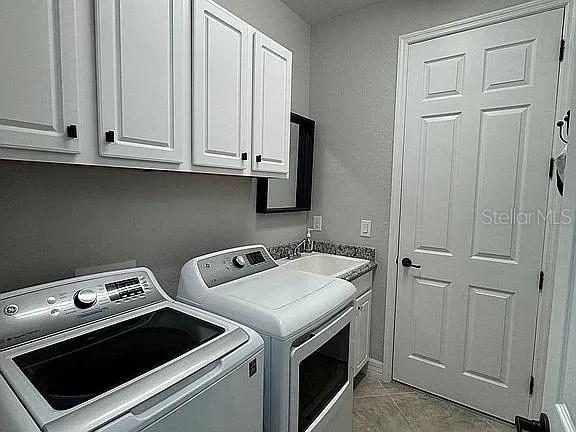 clothes washing area featuring cabinets, washer and clothes dryer, and sink