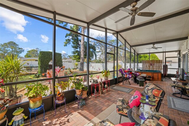 sunroom / solarium with lofted ceiling, a healthy amount of sunlight, and ceiling fan