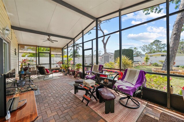 sunroom with ceiling fan and vaulted ceiling with beams