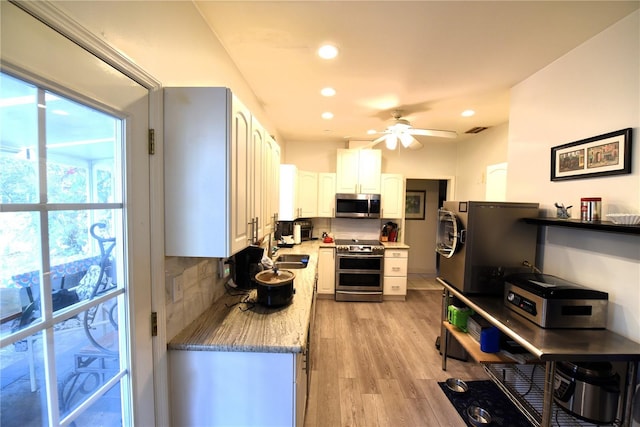 kitchen featuring light hardwood / wood-style flooring, ceiling fan, appliances with stainless steel finishes, white cabinetry, and backsplash