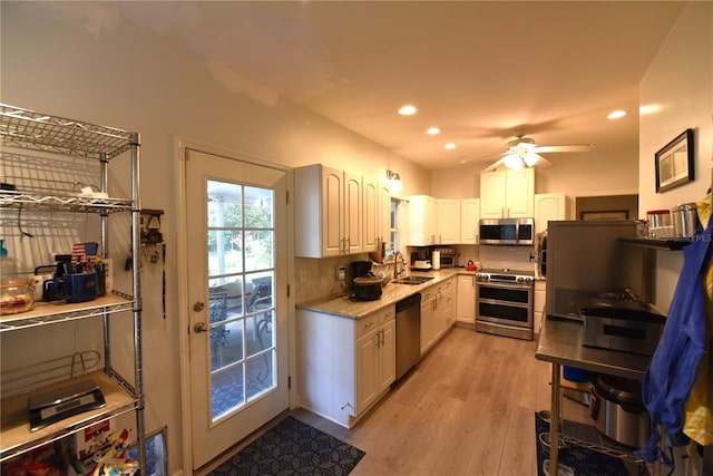 kitchen featuring sink, light hardwood / wood-style flooring, backsplash, stainless steel appliances, and white cabinets