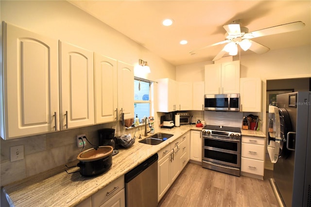 kitchen featuring sink, white cabinetry, light wood-type flooring, appliances with stainless steel finishes, and decorative backsplash