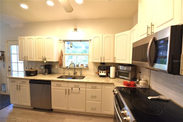 kitchen featuring sink, light hardwood / wood-style flooring, stainless steel appliances, white cabinets, and decorative backsplash