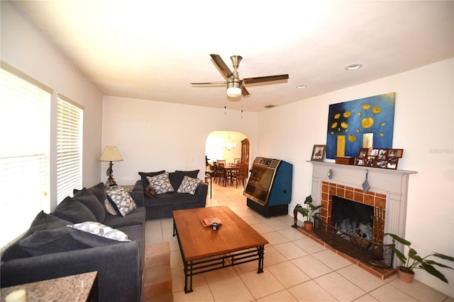 tiled living room with a tiled fireplace and ceiling fan