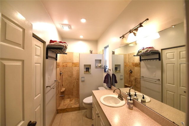 bathroom with vanity, toilet, tile patterned flooring, and a tile shower