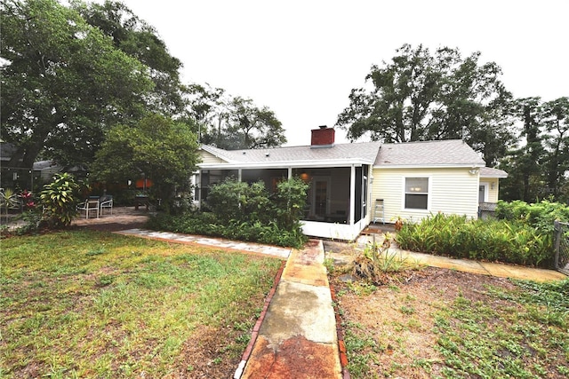 back of house featuring a yard and a sunroom