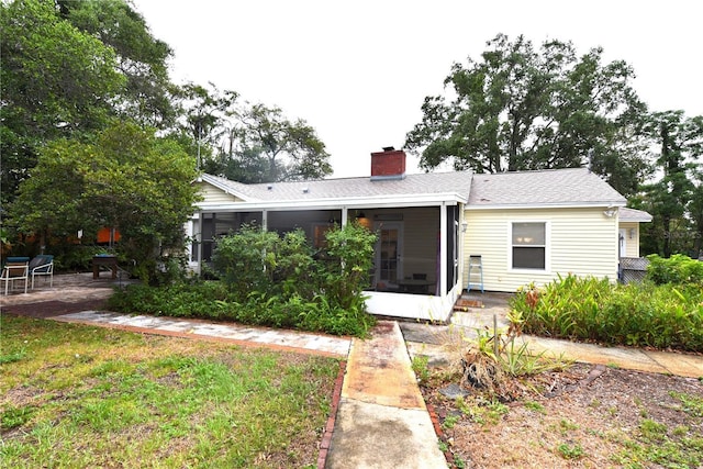 rear view of house with a patio, a yard, and a sunroom