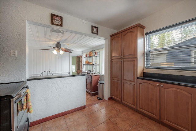 kitchen featuring light tile patterned flooring, ceiling fan, and stainless steel electric stove