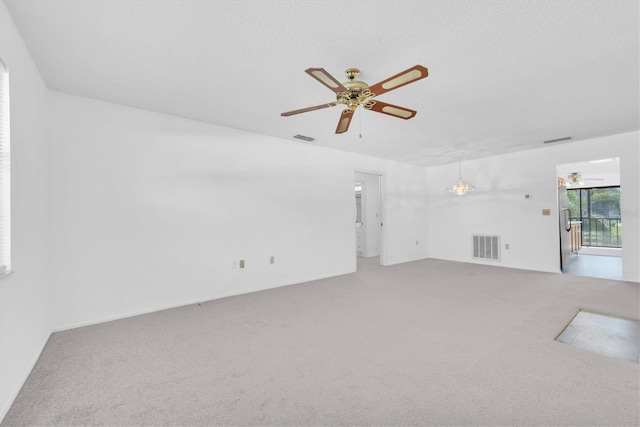 carpeted empty room with ceiling fan, visible vents, and a textured ceiling