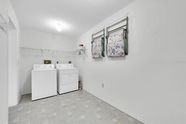 washroom with laundry area, independent washer and dryer, a textured ceiling, and baseboards