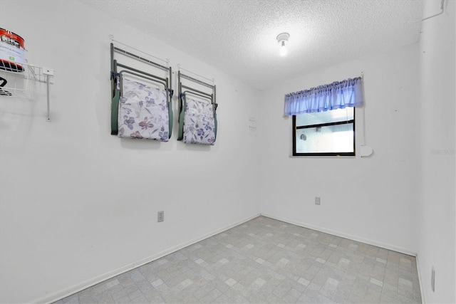 unfurnished room with a textured ceiling, baseboards, and tile patterned floors