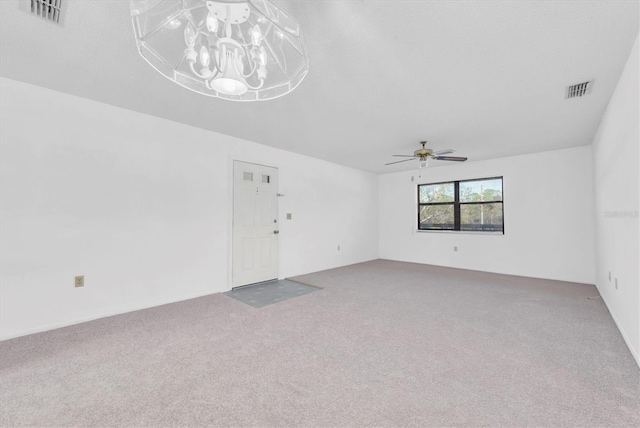 unfurnished room with carpet, visible vents, and ceiling fan with notable chandelier