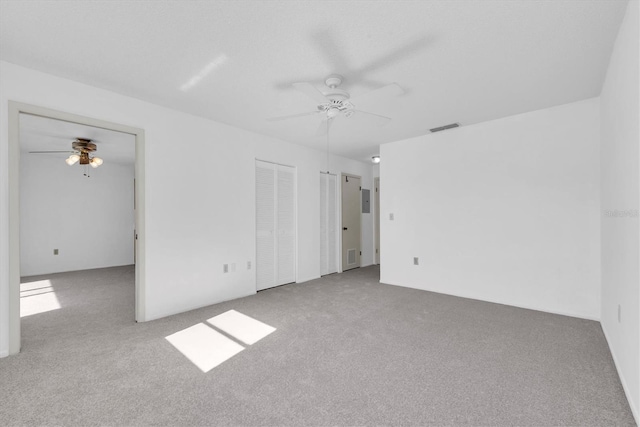 carpeted empty room with ceiling fan and visible vents