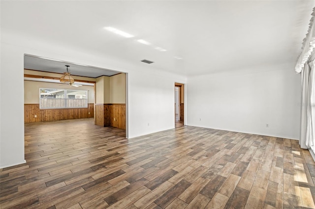 unfurnished living room featuring wood-type flooring and wood walls